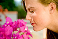 girl breathing in the scent of a pink flower